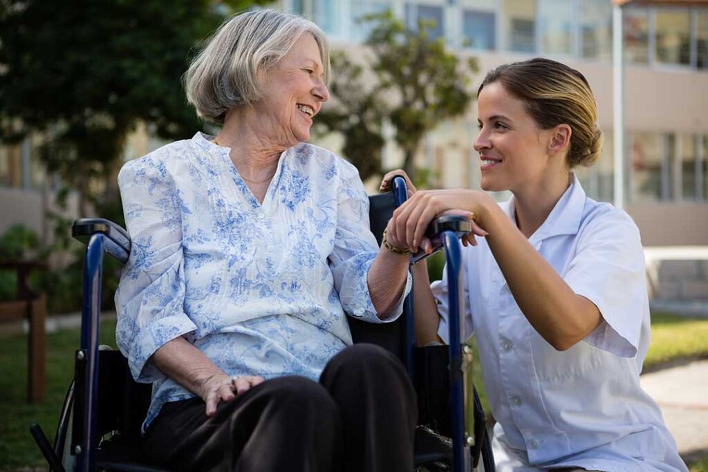 Older resident choosing clothing with a caregiver in a bright assisted living room.